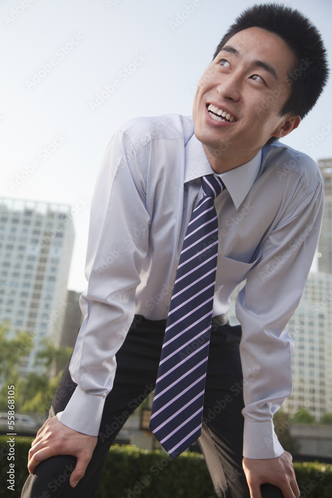 Young businessman bending forward, outside in the business district, Beijing