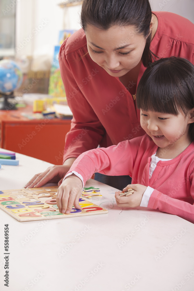 Teaching Helping Young Girl with Cut-Out Alphabet Letters Teaching Helping Young Girl with Cut-Out Alphabet Letters