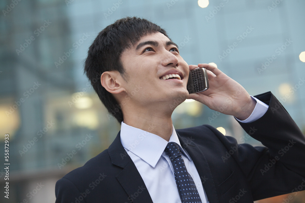 Young smiling businessman on the phone looking up Young smiling businessman on the phone looking up