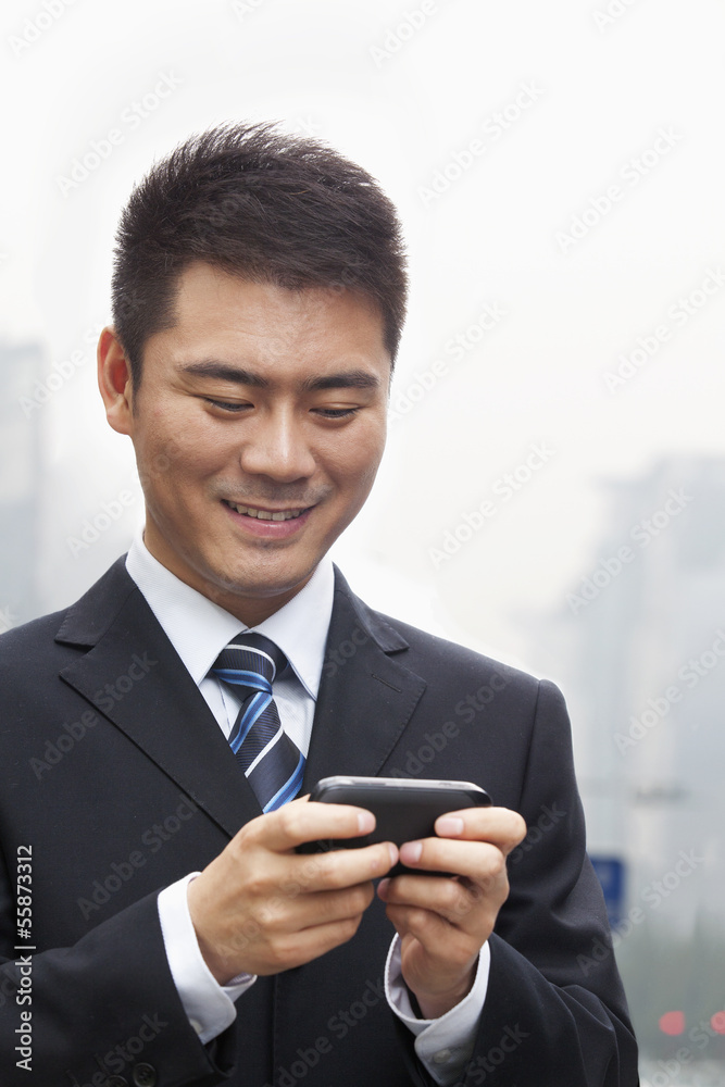Young Businessman Smiling and Using a Smart Phone Young Businessman Smiling and Using a Smart Phone