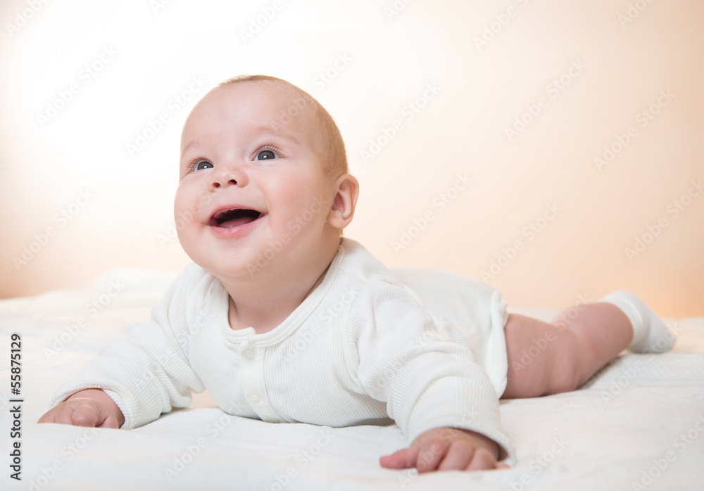 cute little smiling baby lying on the blanket, orange background
