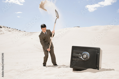 Fotografia Man digging by safe in desert