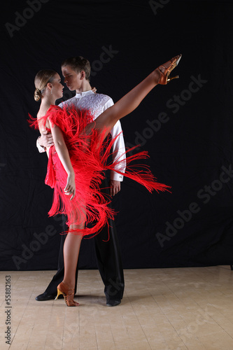 Latino dancers in ballroom against black background