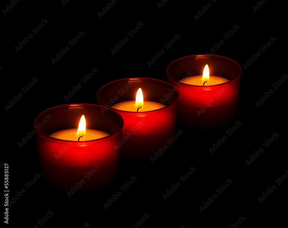 Red votive candles burning in the dark, black background Red votive candles burning in the dark, black background