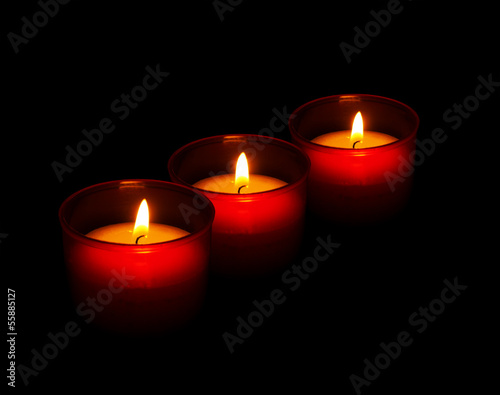 Red votive candles burning in the dark, black background