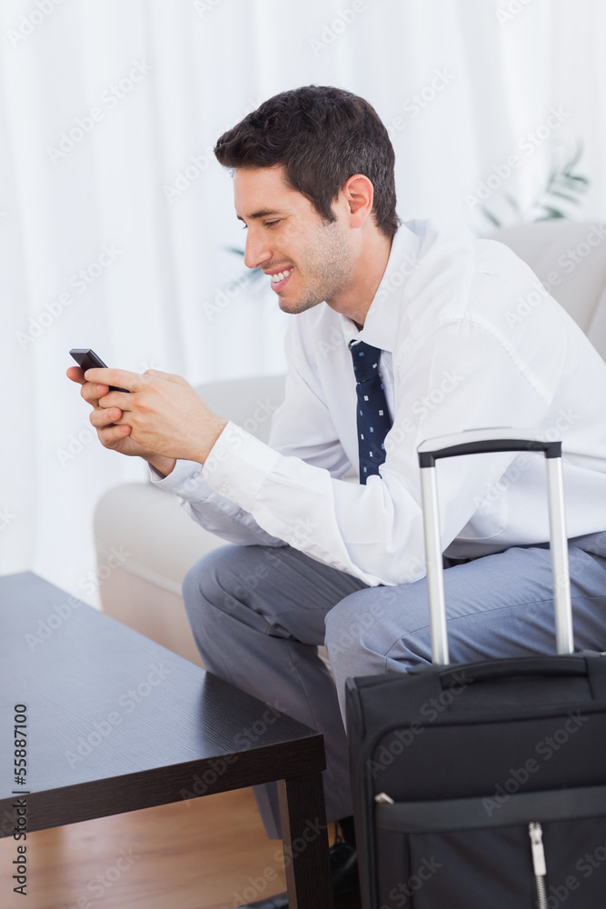 Businessman with his suitcase using mobile phone smiling Businessman with his suitcase using mobile phone smiling