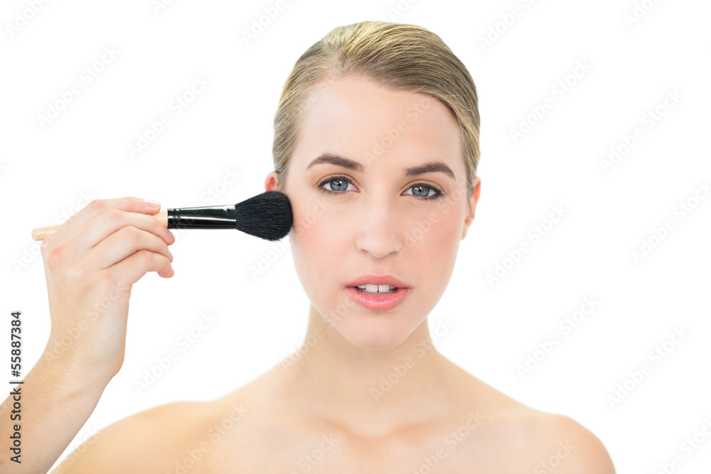 Attractive blonde applying blusher on her cheeks Attractive blonde applying blusher on her cheeks