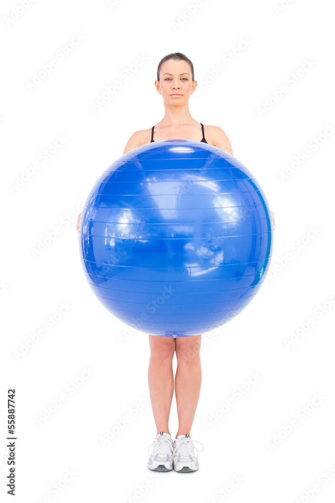 Relaxed fit woman holding exercise ball in front of her Relaxed fit woman holding exercise ball in front of her
