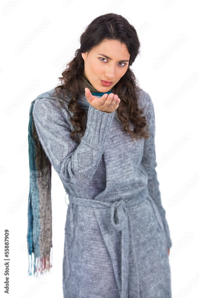 Peaceful curly haired model with winter clothes kissing at camer Peaceful curly haired model with winter clothes kissing at camer