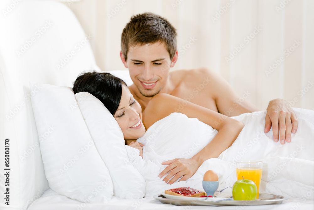 Lying man serves woman breakfast in bedroom Lying man serves woman breakfast in bedroom