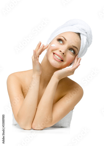 Female with towel on head applies cream on face