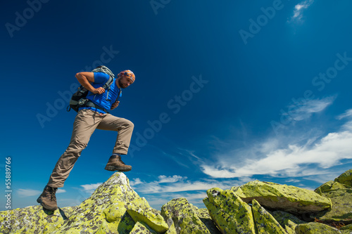 Hiker jumps over stones in mountains