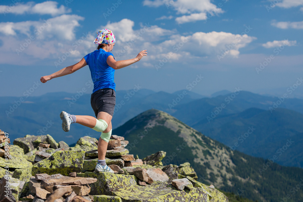 Woman athlete is jumping over stones in mountains Woman athlete is jumping over stones in mountains
