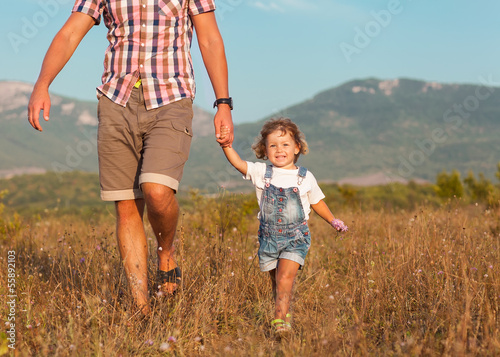 Father and daughter walking on the field 