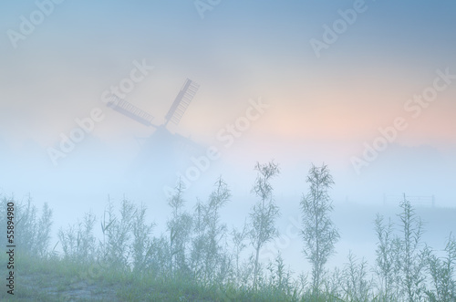 Dutch windmill in dense sunrise fog