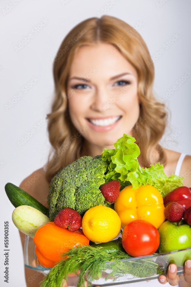 Young woman with vegetarian food, over gray