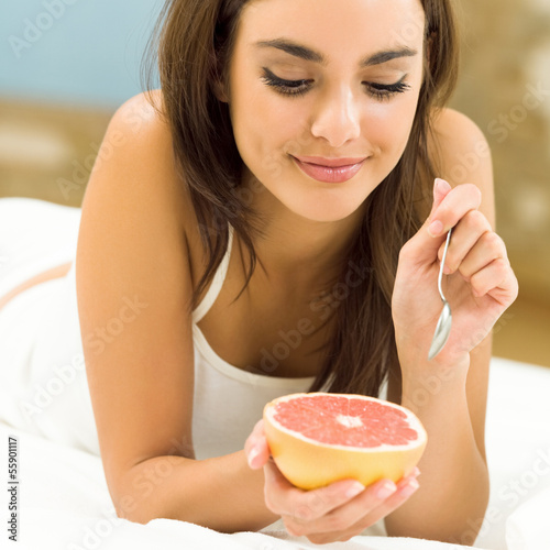 Portarit of woman eating grapefruit at home