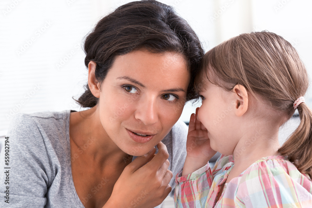 A little girl telling her mother a secret