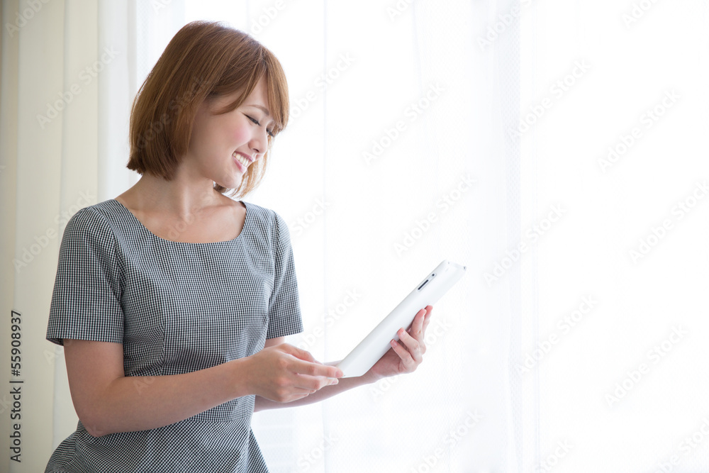 窓際でタブレットを見る女性 窓際でタブレットを見る女性