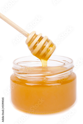 Honey dripping into a jar with a special spoon.