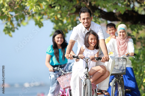 Family with kids enjoy riding bicycle outdoor in the beach