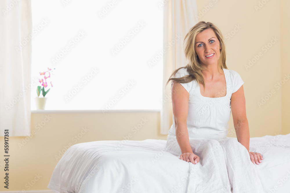 Happy woman looking at camera and sitting on a bed Happy woman looking at camera and sitting on a bed