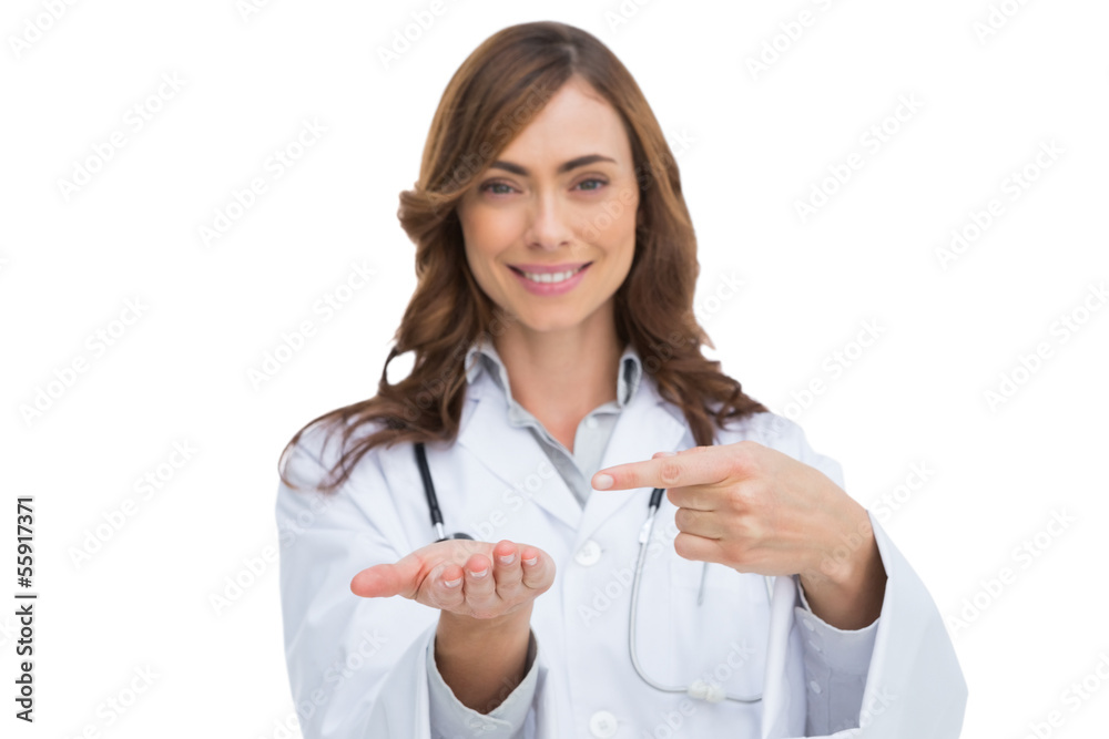 Smiling doctor pointing at something in her hand Smiling doctor pointing at something in her hand