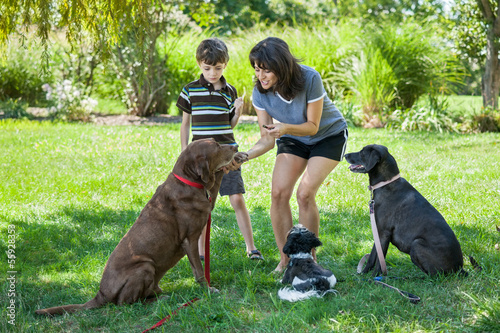 Canvas Print Mother and son training three dogs with treats