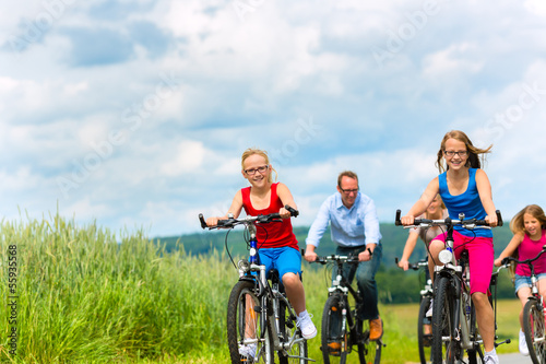 Family cycling in summer in rural landscape