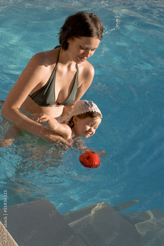 The baby girl play with her mother  in pool