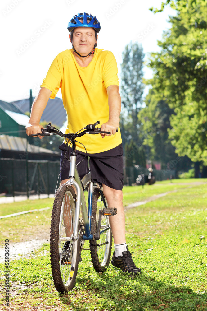 Obraz premium Full length portrait of a mature man in sportswear on his bike