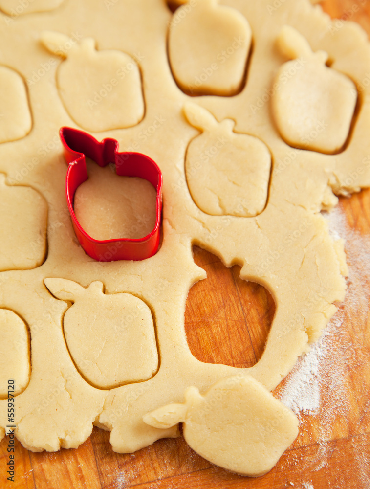 Apple shaped cookie cutter on raw cookie dough Apple shaped cookie cutter on raw cookie dough