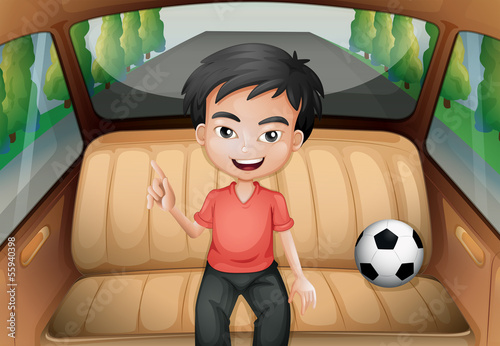 A boy inside the car with a soccer ball
