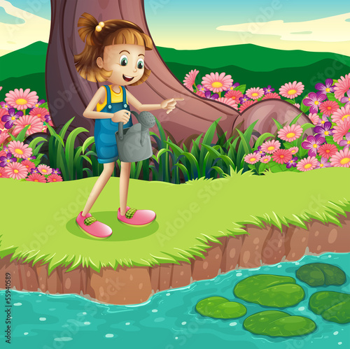 A young girl standing at the riverbank holding a sprinkler