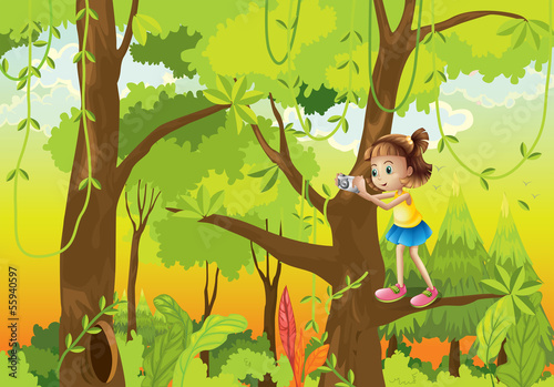 A girl standing at the branch of a tree with a camera