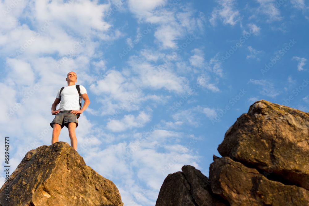 Man standing on a tall rock surveying the world Man standing on a tall rock surveying the world