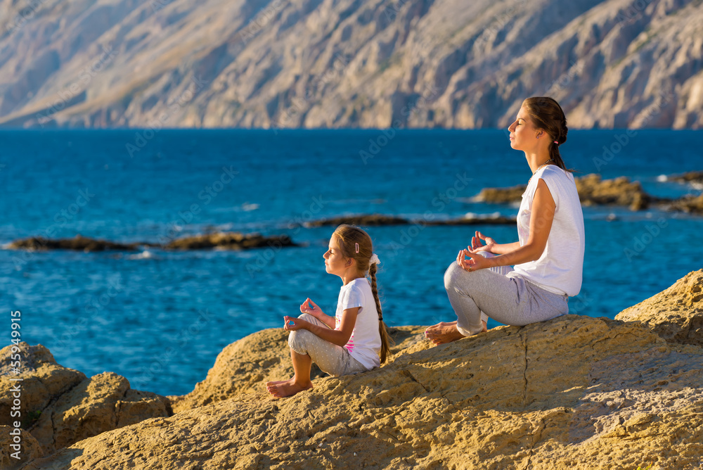 Mother and daughter doing yoga exercise on the beach Mother and daughter doing yoga exercise on the beach