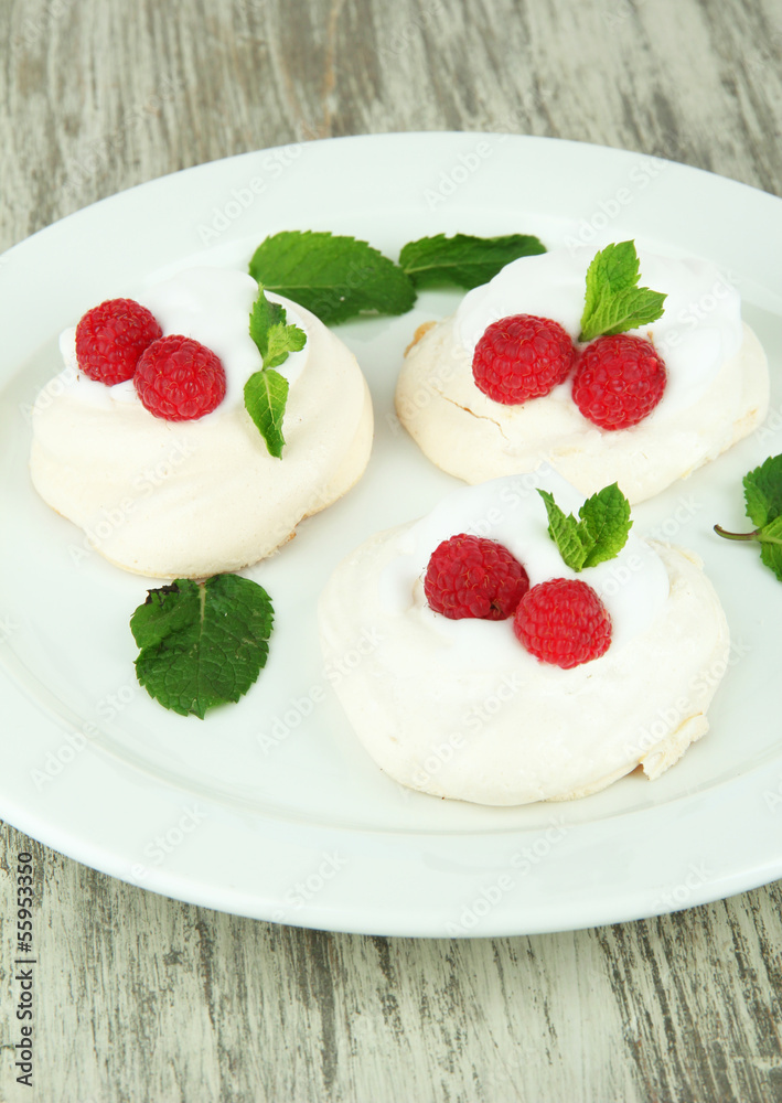 Tasty meringue cakes with berries on wooden table Tasty meringue cakes with berries on wooden table