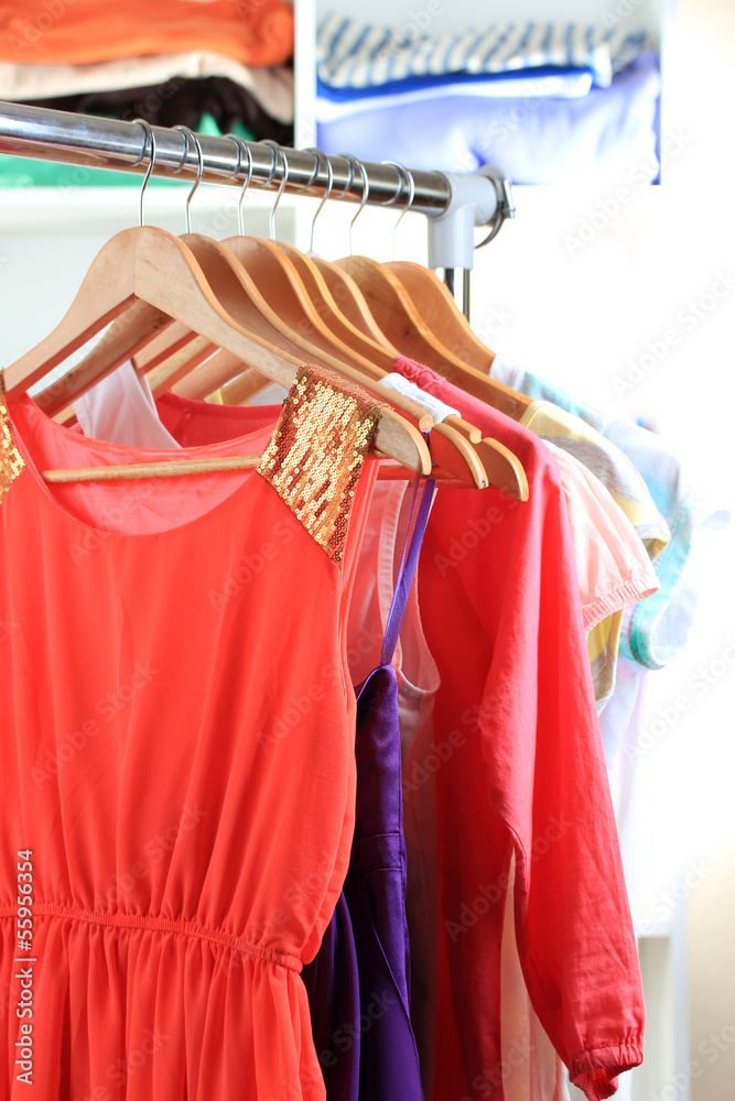 Variety of clothes on wooden hangers on shelves background Variety of clothes on wooden hangers on shelves background