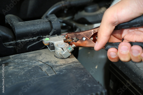 Car mechanic uses battery jumper cables to charge dead battery © Africa Studio