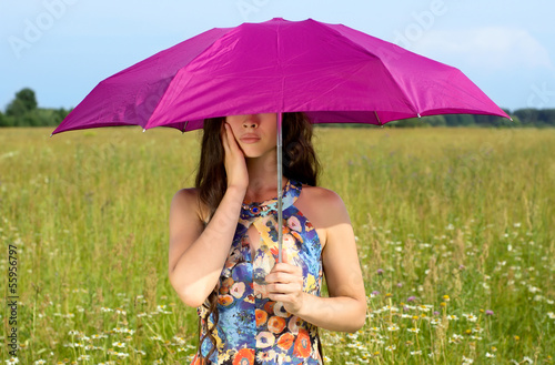 Young woman with umbrella in field © seralex