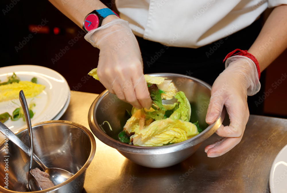 Chef is mixing salad at professional kitchen Chef is mixing salad at professional kitchen