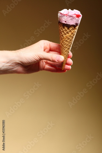 Berry icecream cone in hand on brown