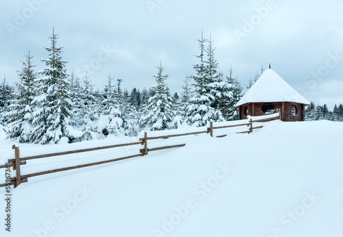 Wooden summerhouse on winter hill top.