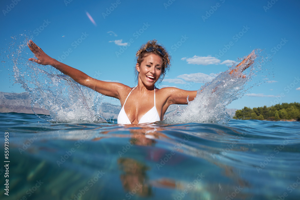Beautiful young woman in the sea splashing water