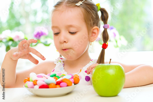 child choosing between apple and sweets