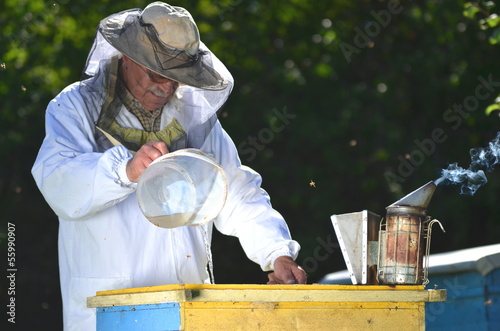Pszczelarz nalewa pszczołom syrop przed okresem zimowym