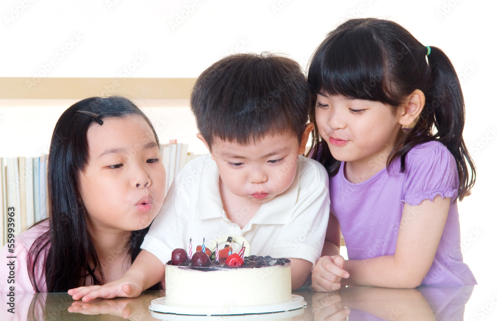 Asian kids blowing candles on a birthday cake Asian kids blowing candles on a birthday cake
