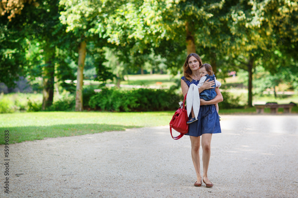 Beautiful mother and little daughter walking in summer park Beautiful mother and little daughter walking in summer park