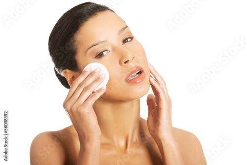 Portrait of happy young woman cleaning skin by cotton pad